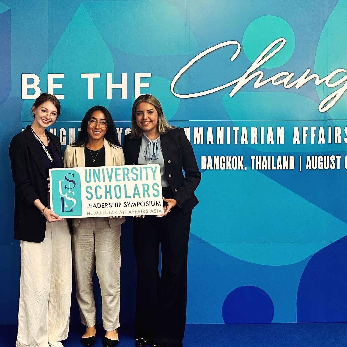 3 students in front of "Be the Change" sign